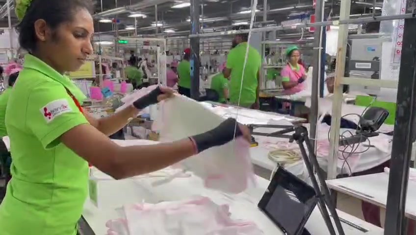 A Brandix operator inspecting a garment beside an Athena station reader